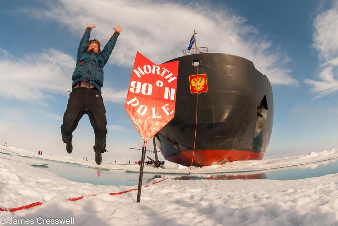 A photograph of James Cresswell, director of GeoWorld Travel, jumping for joy at the geographic North Pole